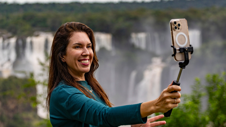 Woman holding a smartphone and gimbal at Niagara Falls