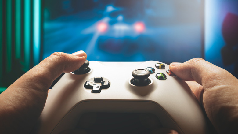 Hands holding an Xbox controller in front of a screen