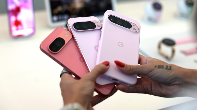 Person holding Pixel 9 series phones.