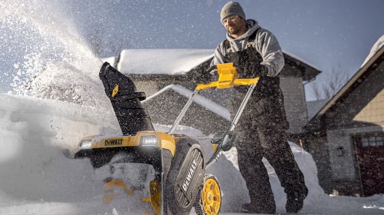 A person using an electric DeWalt snow blower.