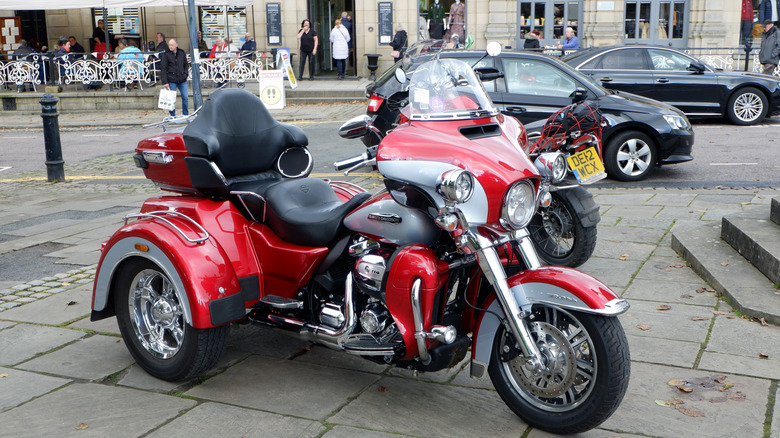 A red Harley-Davidson Trike motorcycle with three wheels standing in a town square.