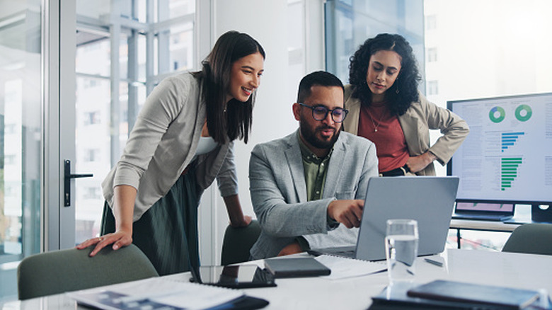 Group of professionals gathered around a laptop