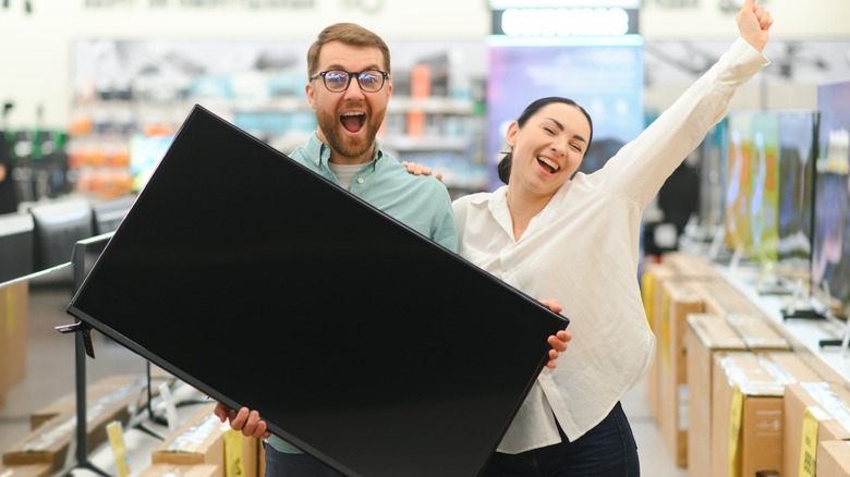 Happy couple holding a TV