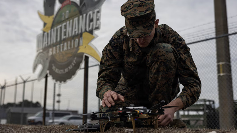 Marine Sgt. Hank Volpe examining drone on ground