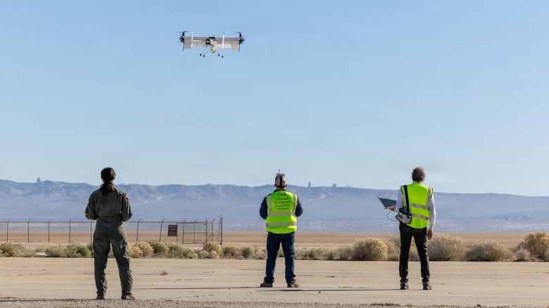 Operators watching a drone hover around 25 feet above the ground.
