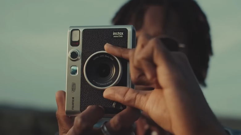 Man adjusting lens on Fujifilm Instax camera