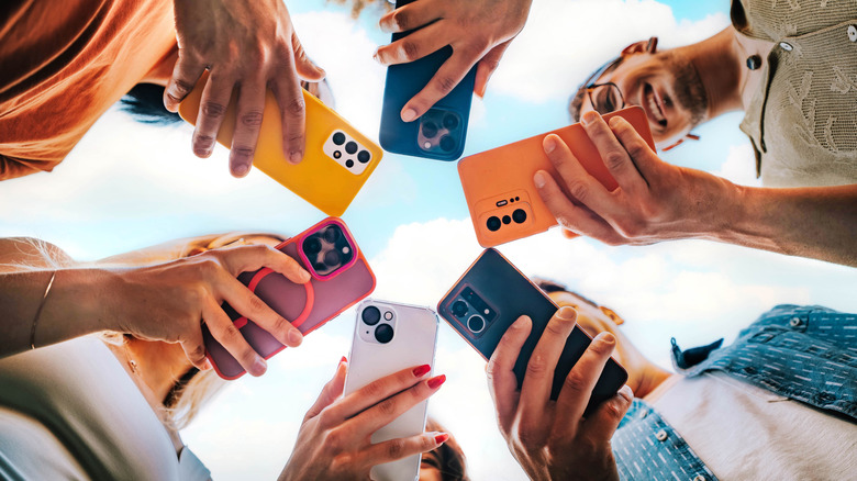 A group of people standing in a circle holding their phones, bottom-up view