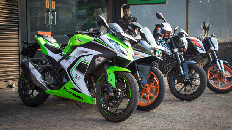 Kawasaki sport motorcycles along with other units from KTM parked in a line at the side of a street.
