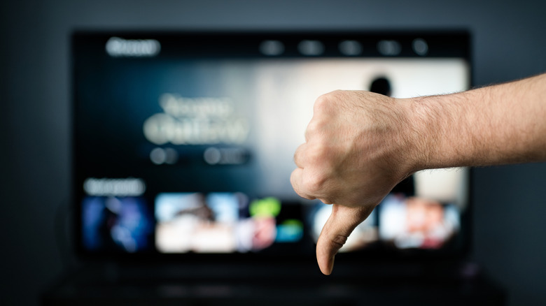 Blurred television with an in-focus hand in front doing the 