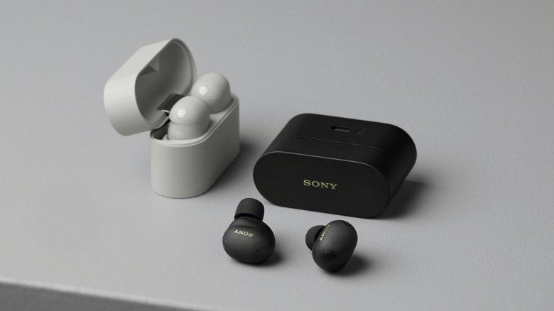 Sony WH-1000XM6 wireless earbuds in black and white on a gray surface