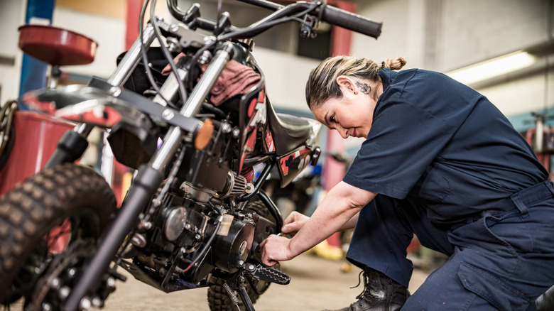 A female mechanic working on a motorcycle in a shop.