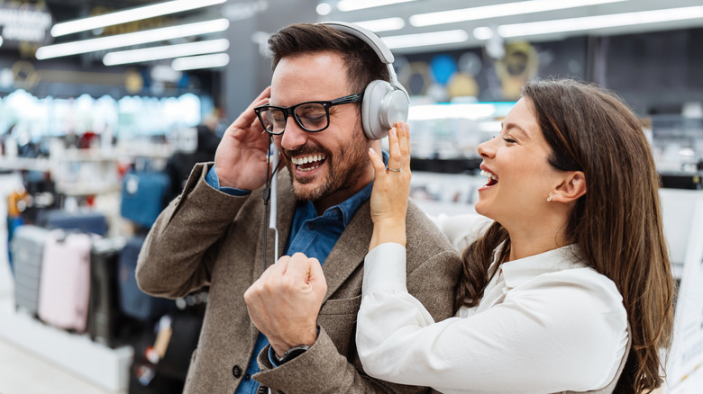 A couple testing out wired headphones in a store.