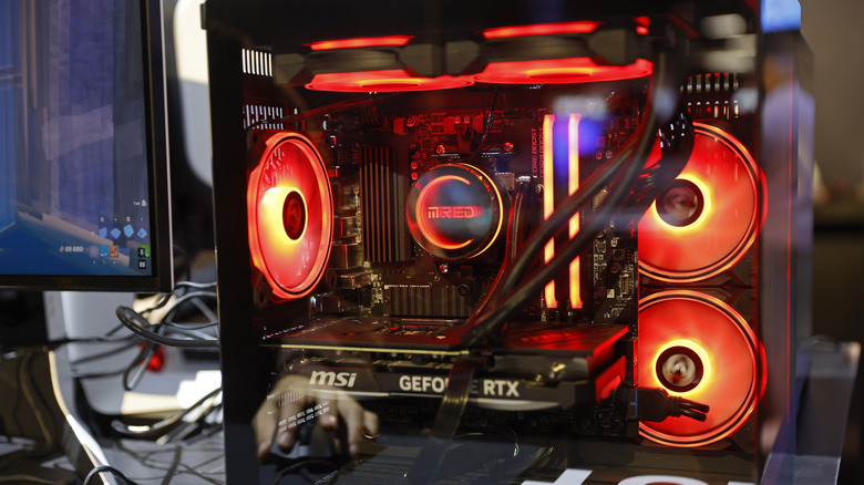 An image of a gaming PC showcasing the graphics card, CPU cooler, and red case fans