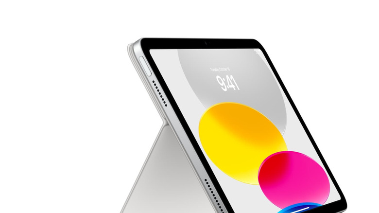 An iPad with the time displayed in front of colorful circles, on a stand.