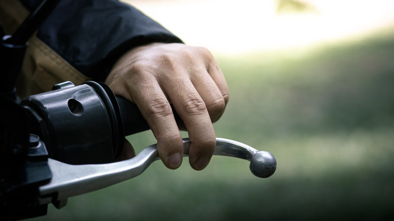 A rider's hand gripping a motorcycle clutch lever.