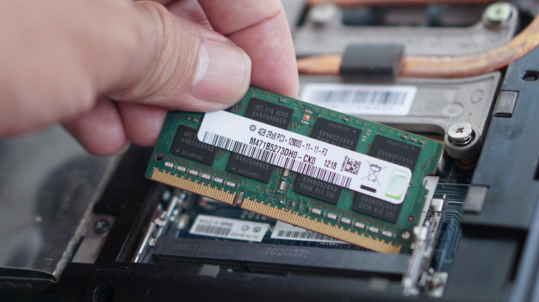Person placing a RAM module inside a laptop