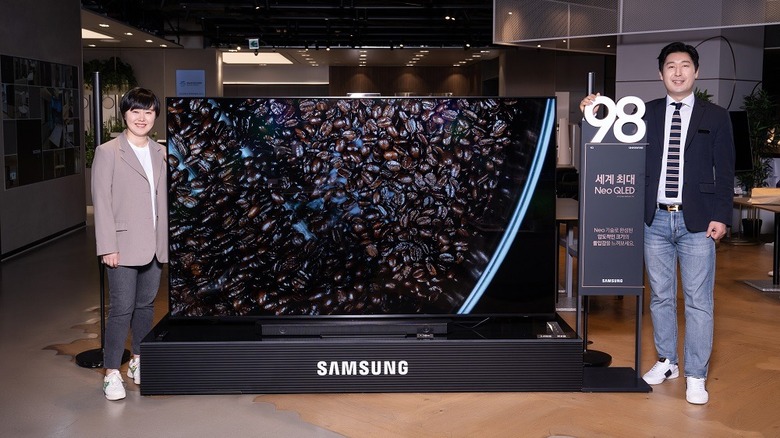 A Samsung 98-inch TV with Samsung employees standing either side.