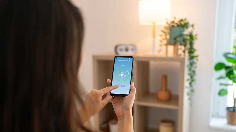 Woman controlling light with a smart phone