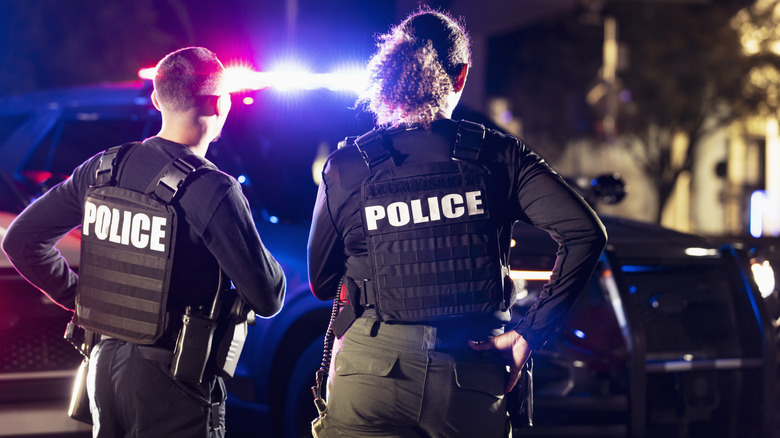 Police officers at a crime scene in front of their cruiser