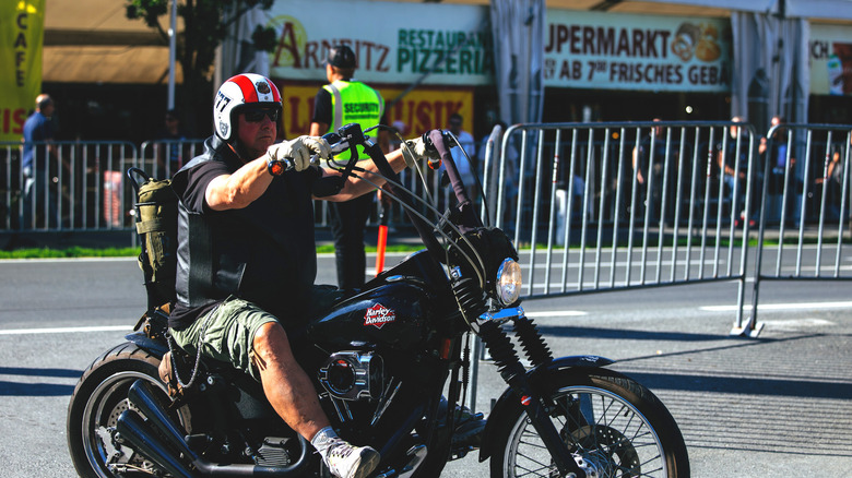 A motorcycle rider wearing shorts.
