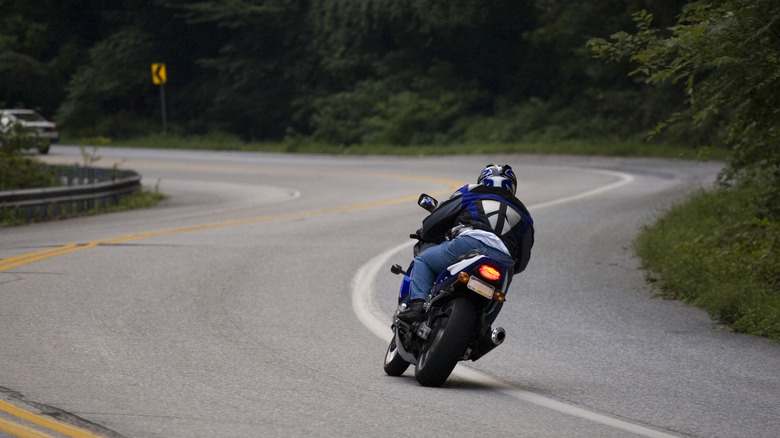 A superbike rider taking a turn on a road.