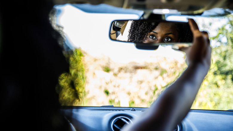 Driver adjusting rear view mirror.
