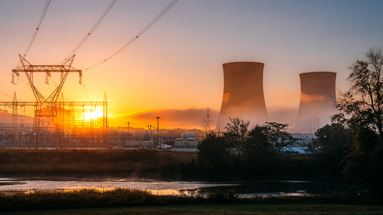 Nuclear cooling towers at sunset, with power lines in the foreground