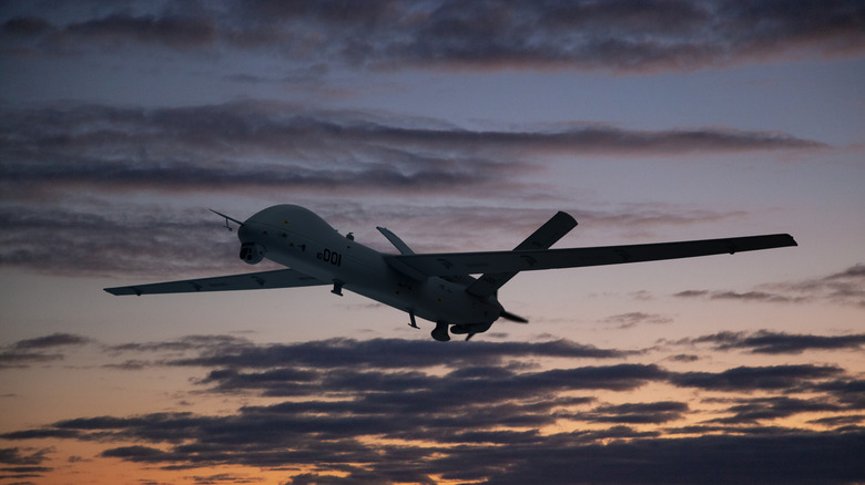 A military combat drone in the sky at sunset