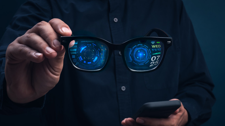 Person holds pair of smart glasses at chest height.