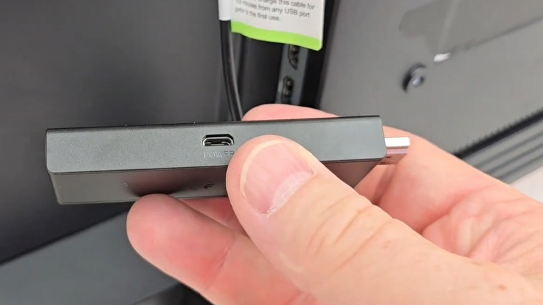 Man holding Fire TV Stick with power port showing