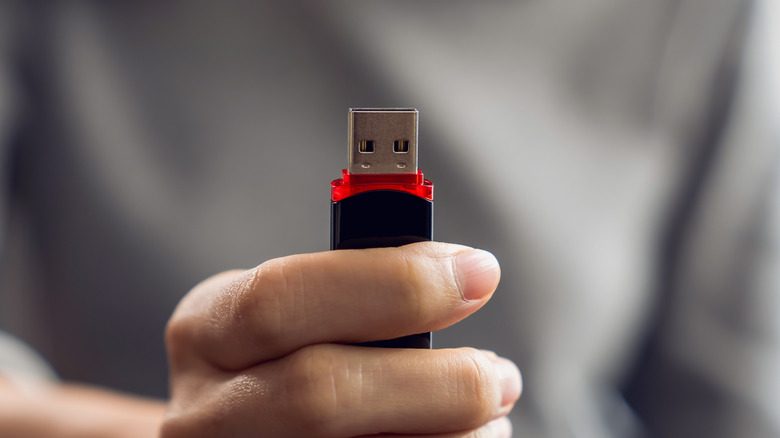 Close-up of a person holding a USB thumb drive.