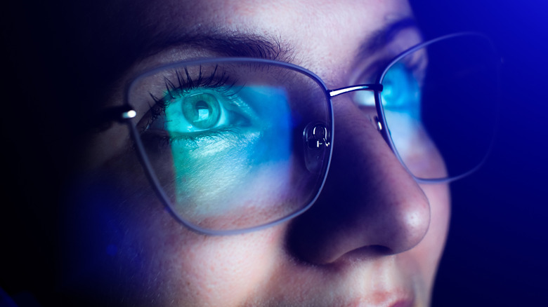 Close up of light from screen reflecting off a person's glasses