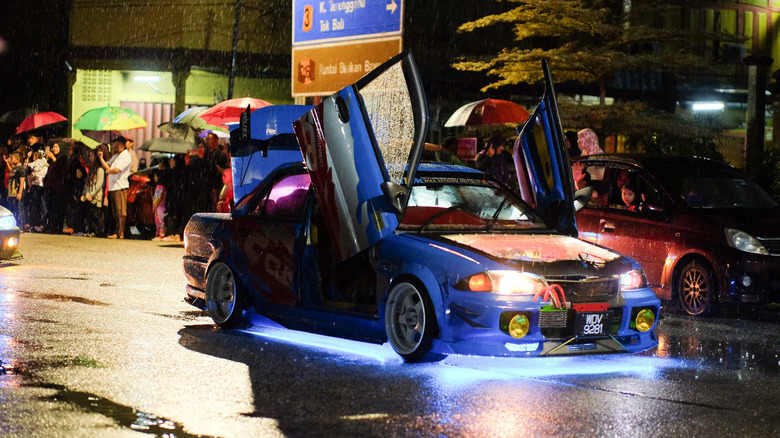 A high-performance car with scissor doors showing off its underglow