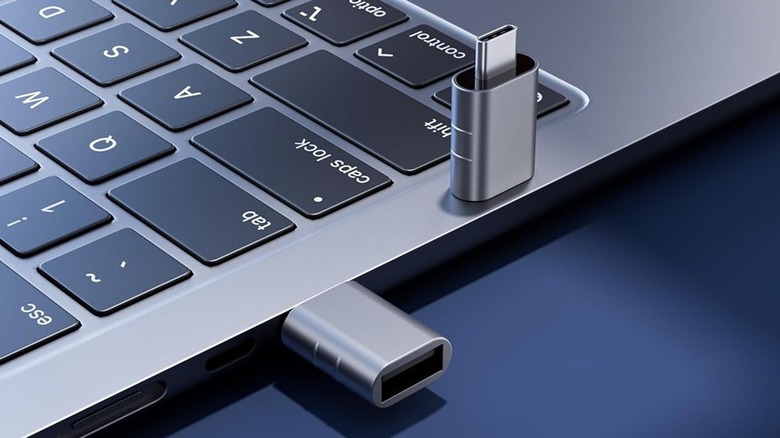 A USB adapter inserted in a laptop and another balanced on it.