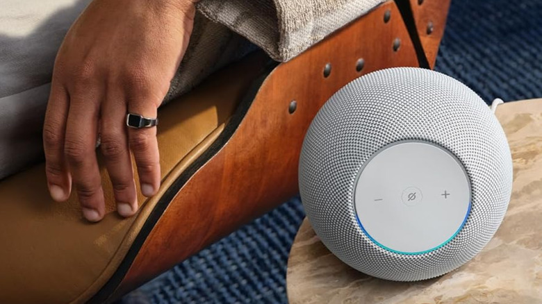 An Amazon Echo Studio on a table near a person.