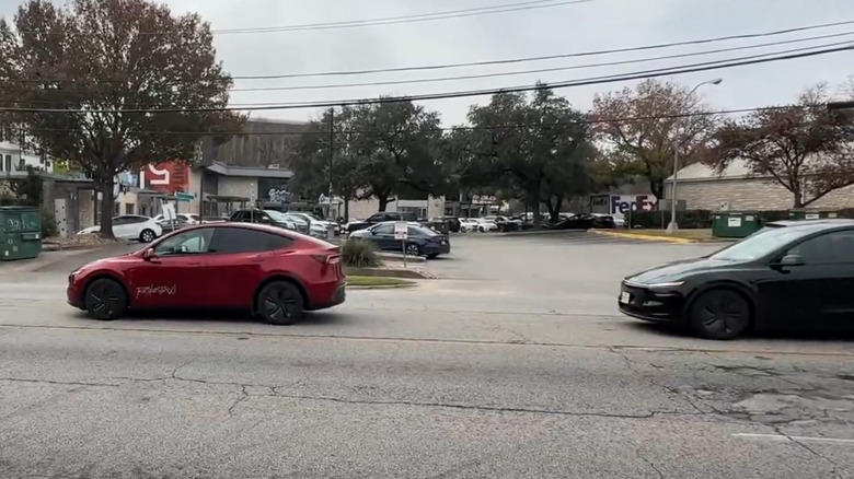 Red Tesla Robotaxi with black Tesla following closely behind