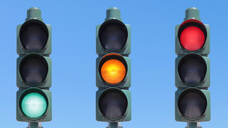 Three traffic signals with green, yellow, and red lights illuminated