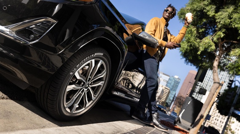 Front 3/4 oblique view of Michelin Defender2 tire on GMC Denali in urban setting