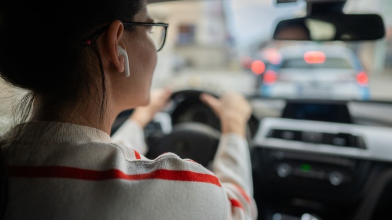 A woman driving with earbuds