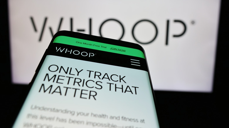 smartphone showing WHOOP's webpage with the company logo in the background
