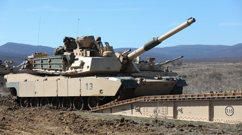 An M1 Abrams tank maneuvring over a ramp.