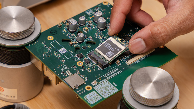 A hand installing a wireless add-on card on to a computer mainboard