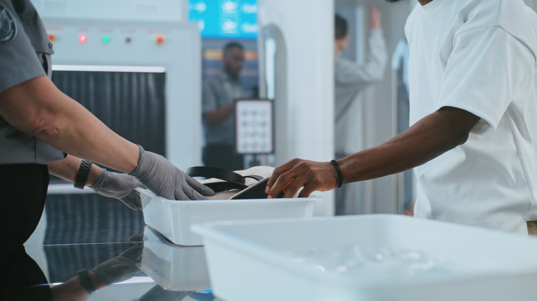 Man removing items and placing them in bin at airport security checkpoint