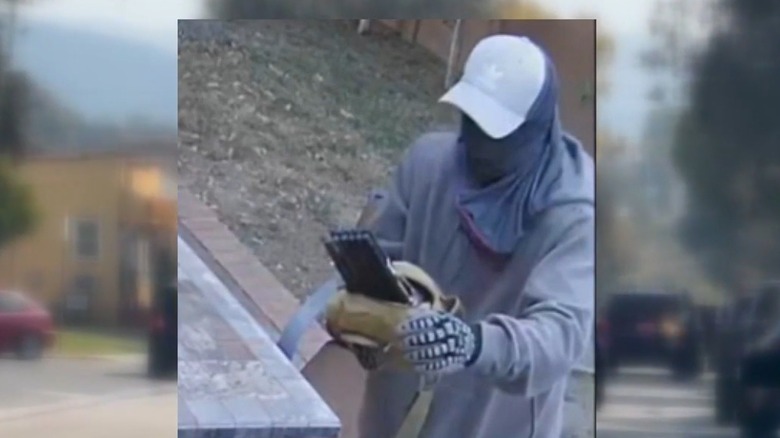A security image of a burglar using a Wi-Fi jammer